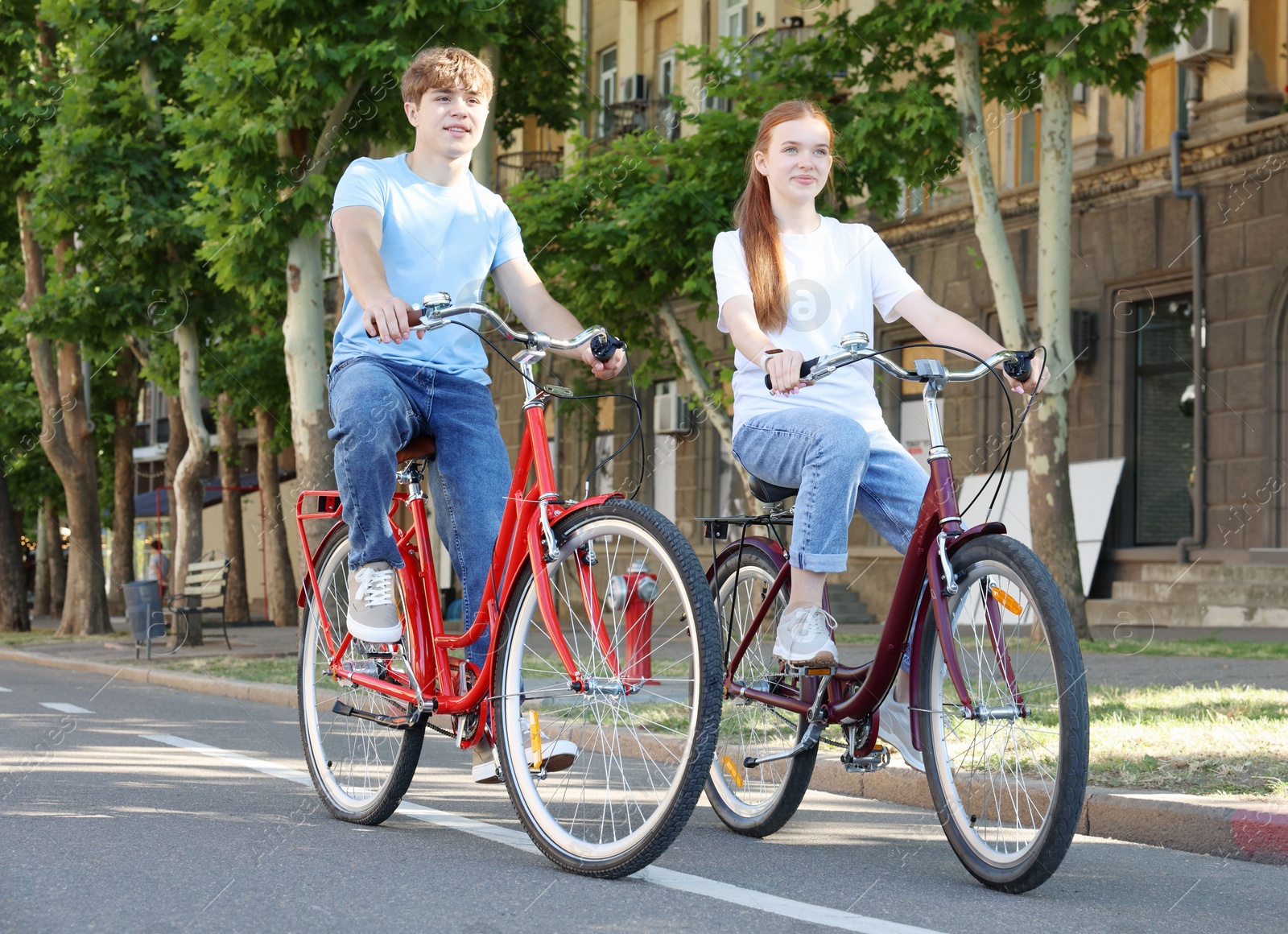 Photo of Teenage girl and boy riding bicycles on city street