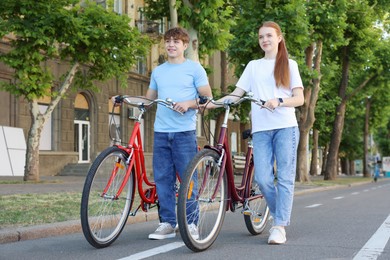 Photo of Teenage girl and boy with bicycles on city street