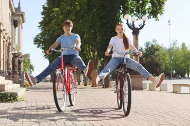 Photo of Teenage girl and boy riding bicycles on city street