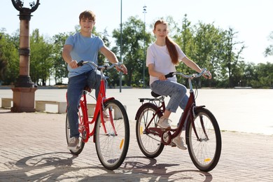 Photo of Teenage girl and boy riding bicycles on city street