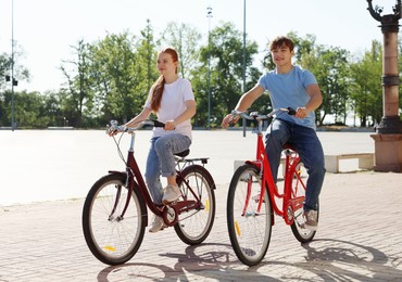 Photo of Teenage girl and boy riding bicycles on city street