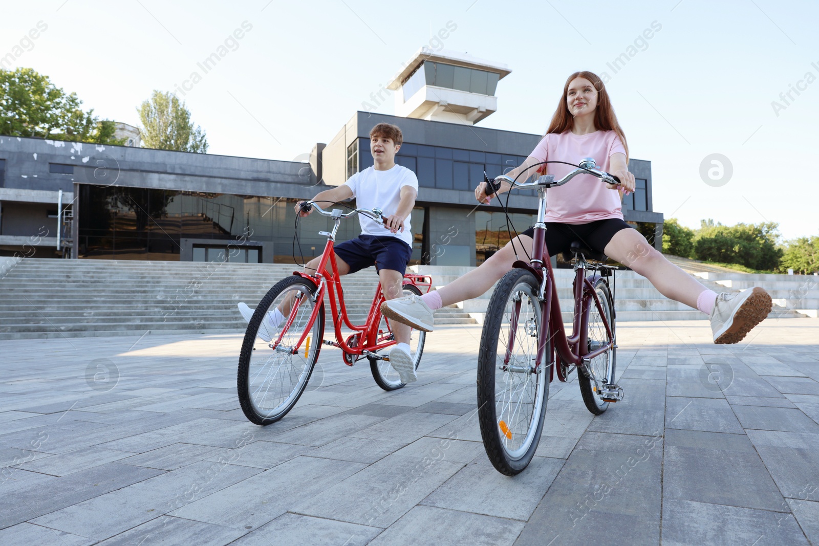 Photo of Teenage girl and boy riding bicycles on city street