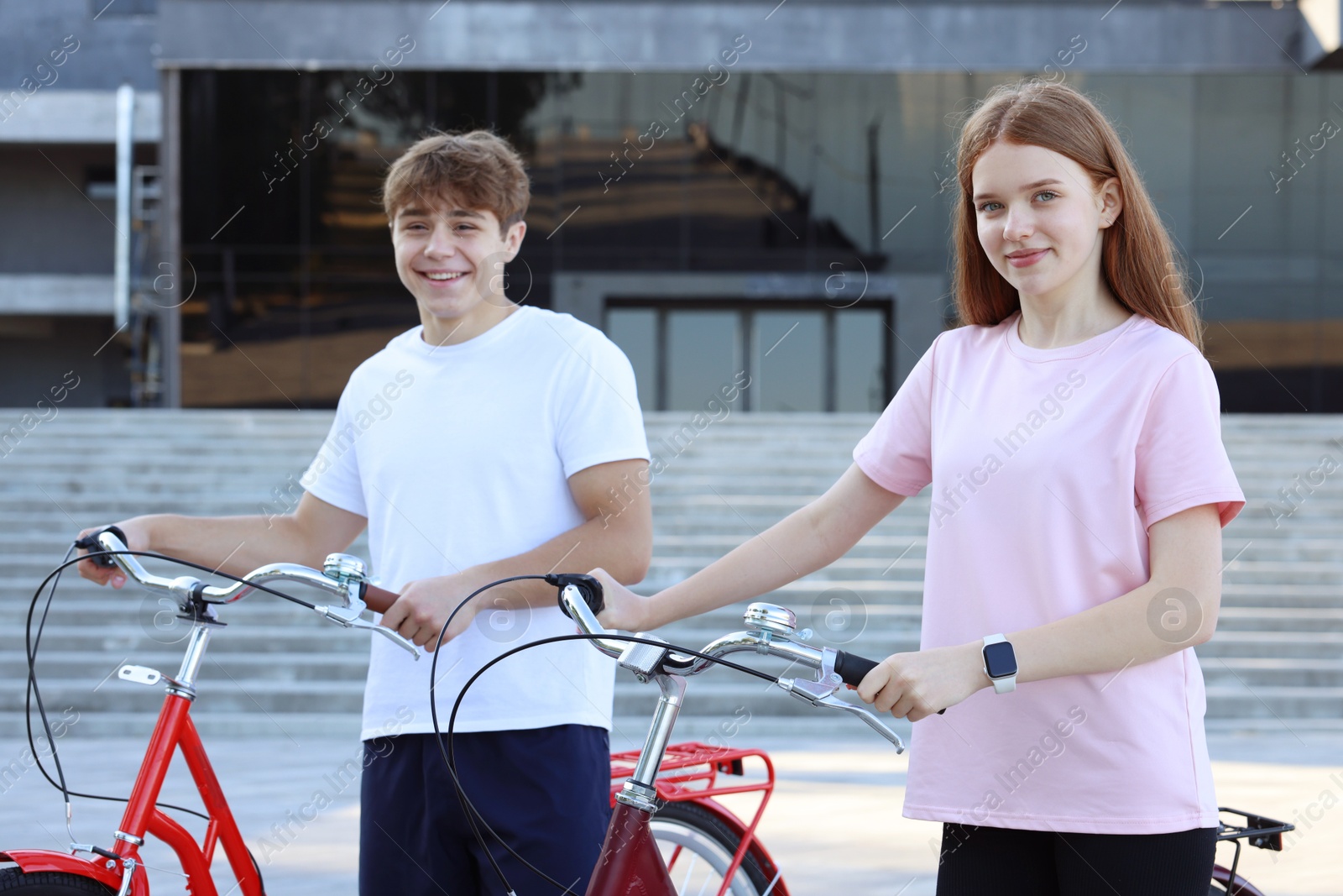 Photo of Teenage girl and boy with bicycles on city street