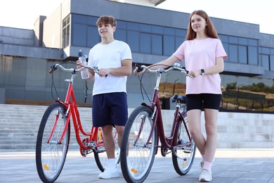 Photo of Teenage girl and boy with bicycles on city street