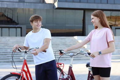 Photo of Teenage girl and boy with bicycles on city street