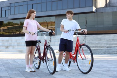 Photo of Teenage girl and boy with bicycles on city street