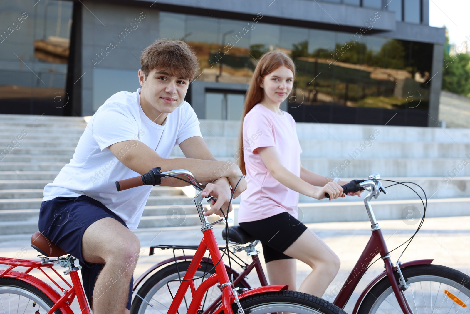 Photo of Teenage girl and boy riding bicycles on city street