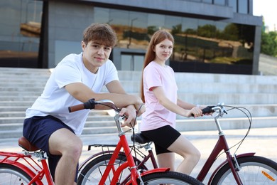 Photo of Teenage girl and boy riding bicycles on city street