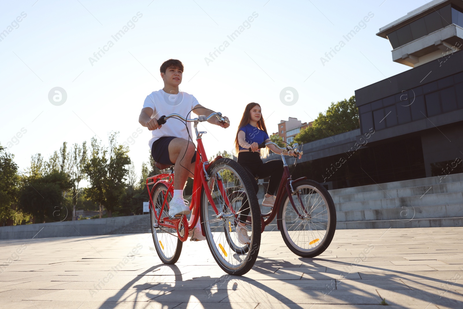 Photo of Teenage girl and boy riding bicycles on city street