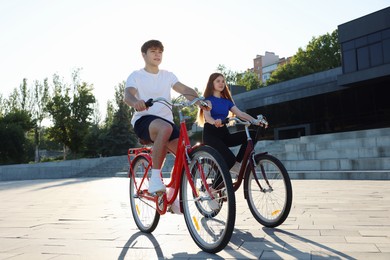 Photo of Teenage girl and boy riding bicycles on city street