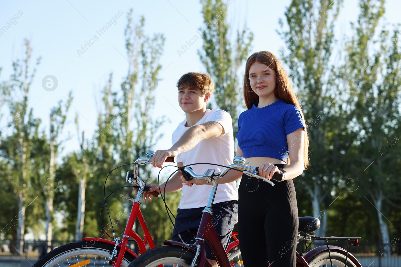 Photo of Teenage girl and boy riding bicycles on city street