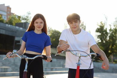 Photo of Teenage girl and boy riding bicycles on city street