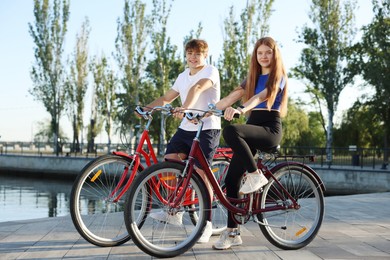 Photo of Teenage girl and boy riding bicycles on city street