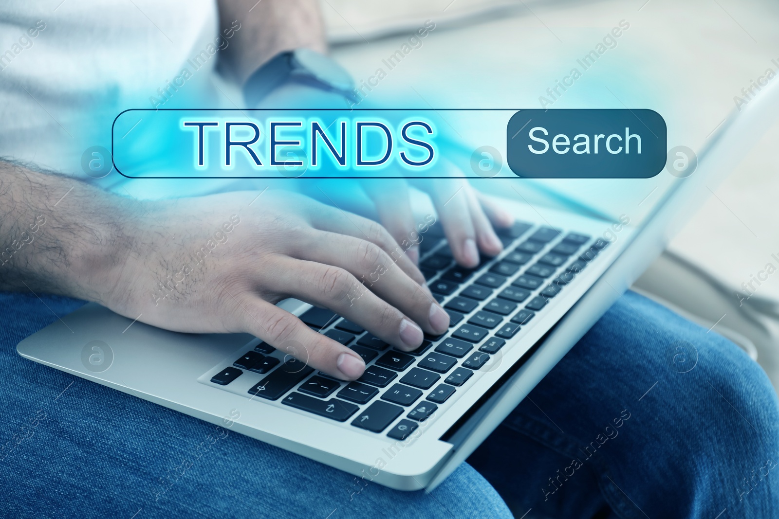 Image of Man using laptop to find hot tendencies, new ideas, popular directions, closeup. Search bar with word Trends