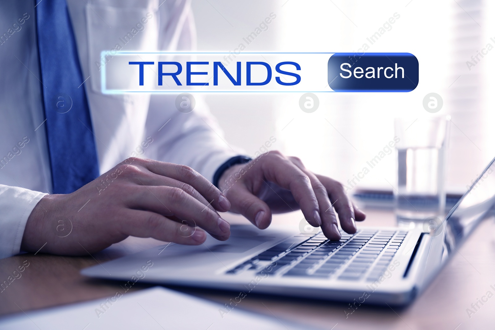 Image of Businessman using laptop to find hot tendencies, new ideas, popular directions at table, closeup. Search bar with word Trends