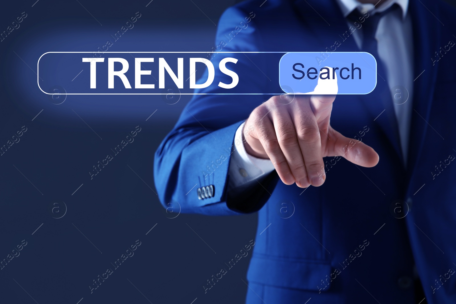 Image of Businessman using virtual screen to find hot tendencies, new ideas, popular directions against dark blue background, closeup. Search bar with word Trends