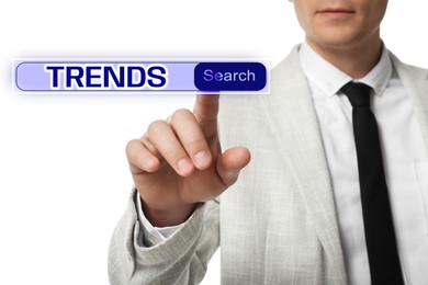Image of Businessman using virtual screen to find hot tendencies, new ideas, popular directions against white background, closeup. Search bar with word Trends