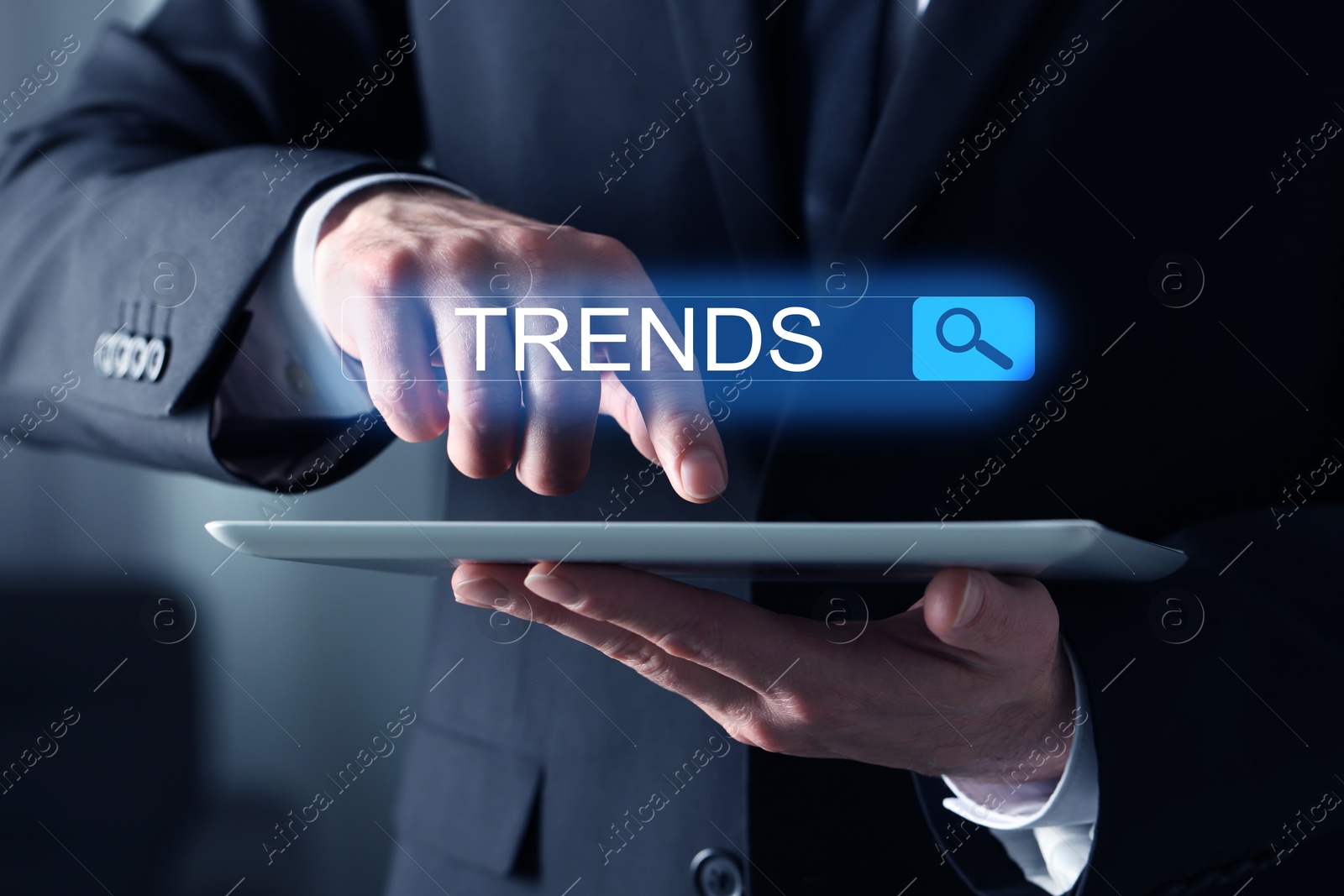 Image of Businessman using tablet computer to find hot tendencies, new ideas, popular directions, closeup. Search bar with word Trends
