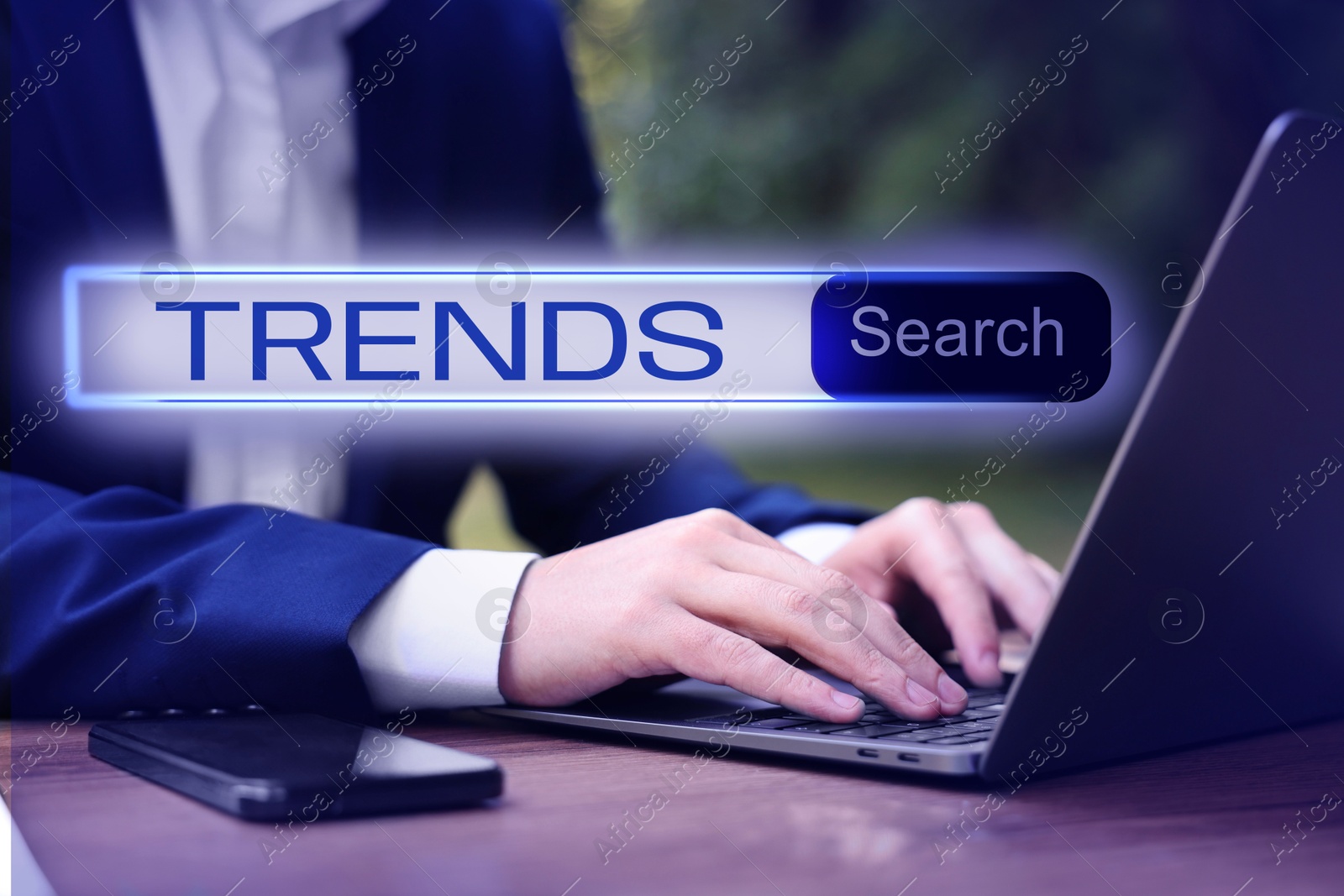 Image of Businessman using laptop to find hot tendencies, new ideas, popular directions at table, closeup. Search bar with word Trends