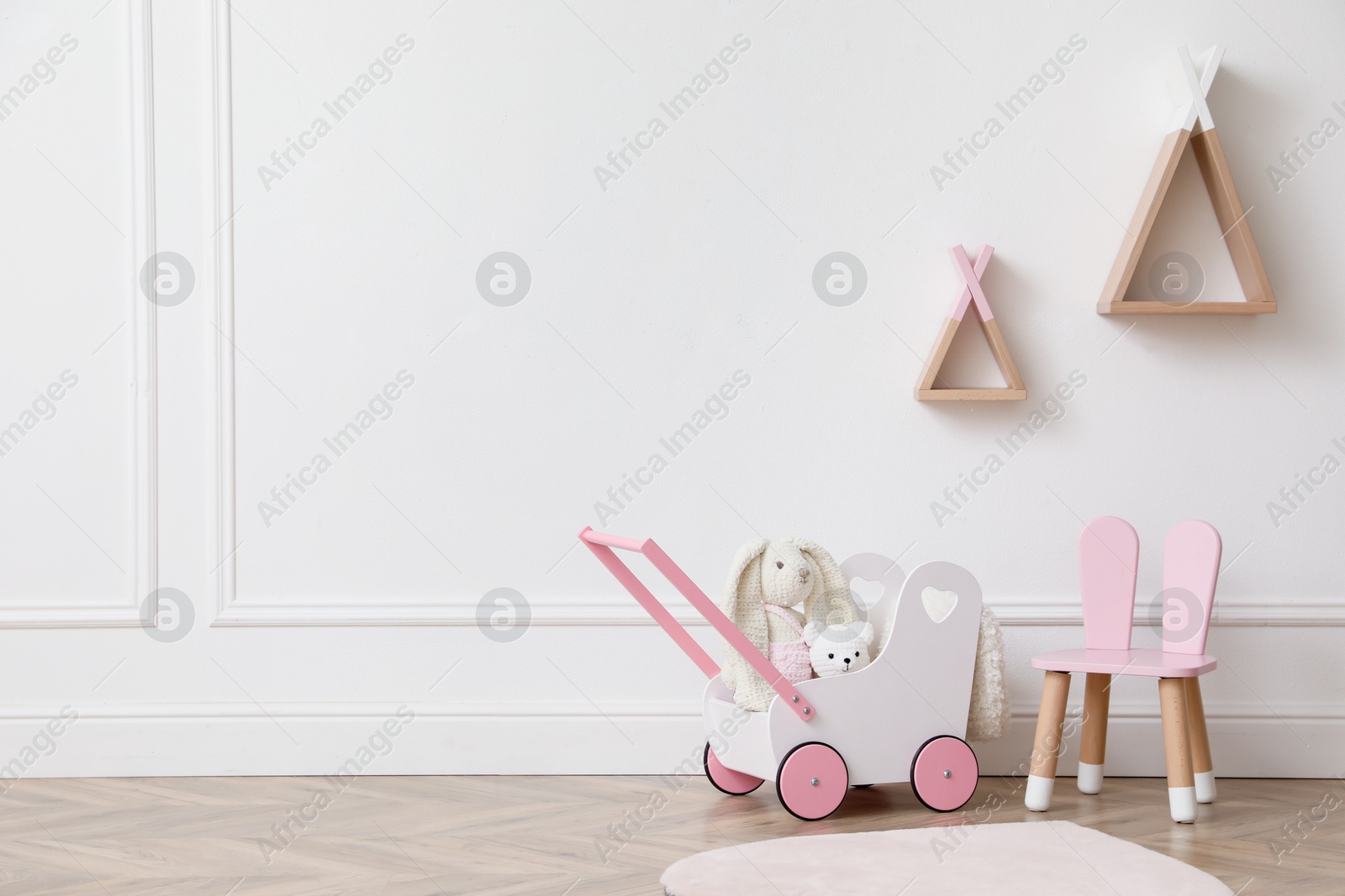 Child's toys, chair and wigwam shaped shelves on white wall indoors. Interior design Photo of Child's toys, chair and wigwam shaped shelves on white wall indoors. Interior design