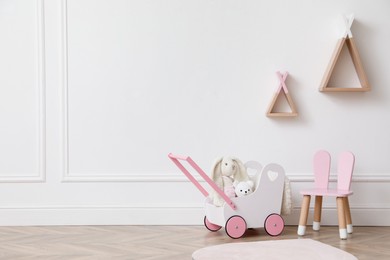 Photo of Child's toys, chair and wigwam shaped shelves on white wall indoors. Interior design
