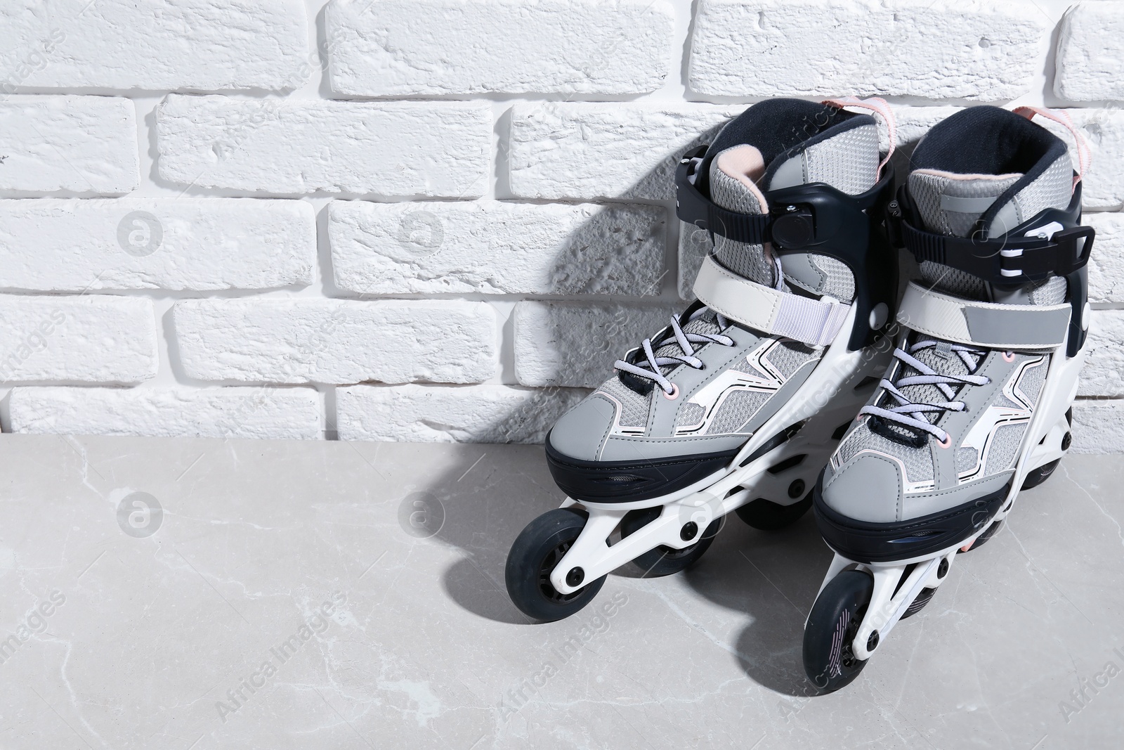Pair of roller skates on grey marble table near white brick wall, above view. Space for text Photo of Pair of roller skates on grey marble table near white brick wall, above view. Space for text