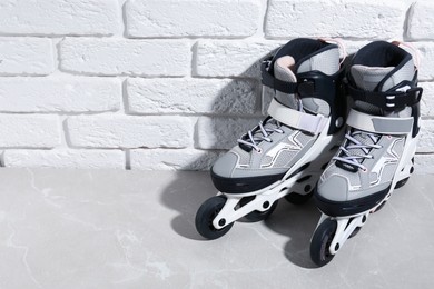 Photo of Pair of roller skates on grey marble table near white brick wall, above view. Space for text