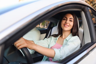 Photo of Woman holding steering wheel while driving car, view from outside