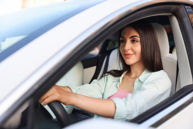 Photo of Woman holding steering wheel while driving car, view from outside