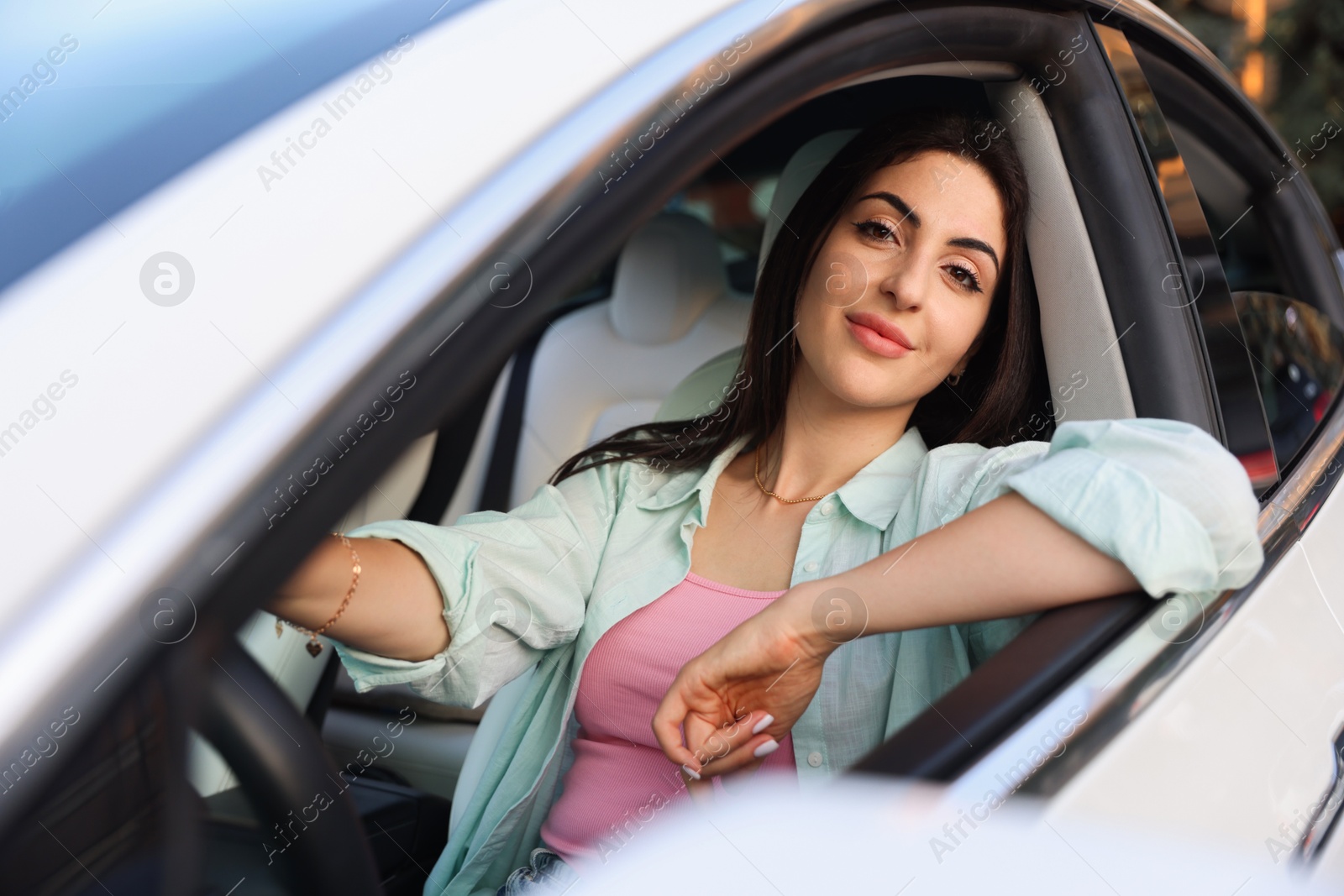 Woman holding steering wheel while driving car, view from outside Photo of Woman holding steering wheel while driving car, view from outside
