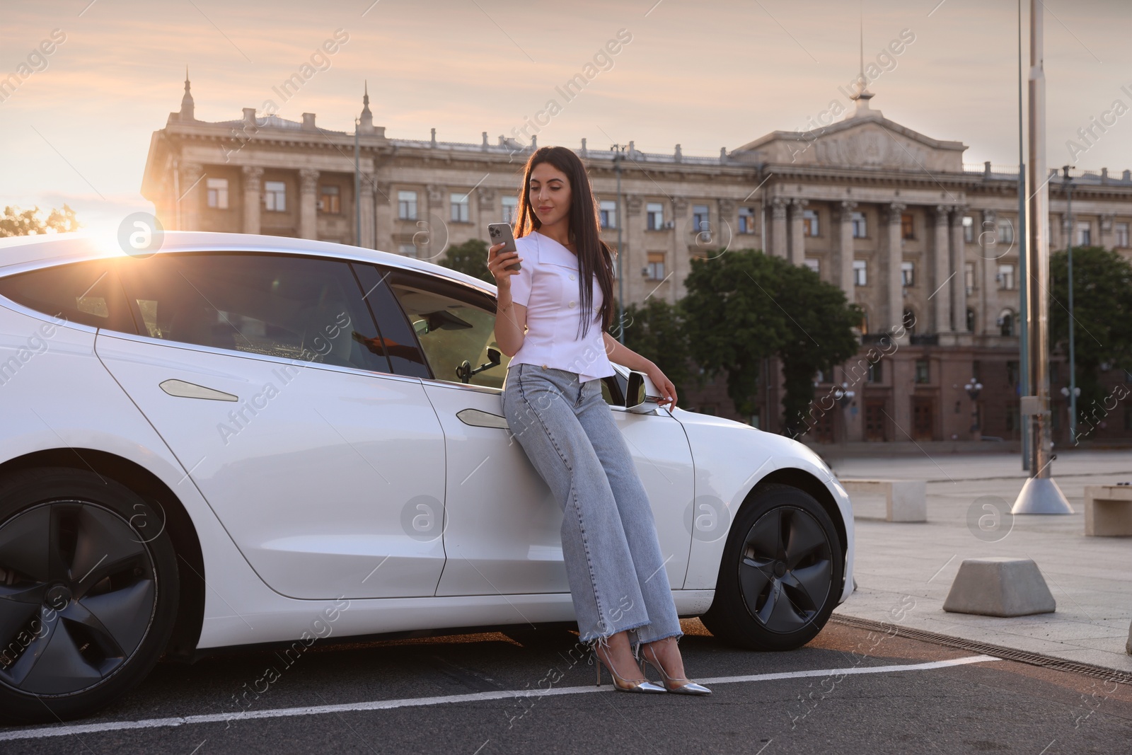 Beautiful woman with smartphone near modern car outdoors on sunny day Photo of Beautiful woman with smartphone near modern car outdoors on sunny day