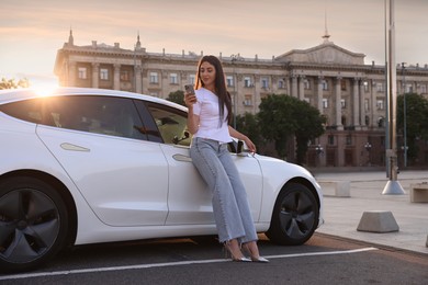 Photo of Beautiful woman with smartphone near modern car outdoors on sunny day