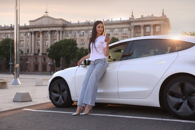Photo of Beautiful woman with smartphone near modern car outdoors on sunny day