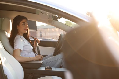 Photo of Woman fastening seat belt in modern car, view from outside