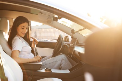 Photo of Woman fastening seat belt in modern car, view from outside