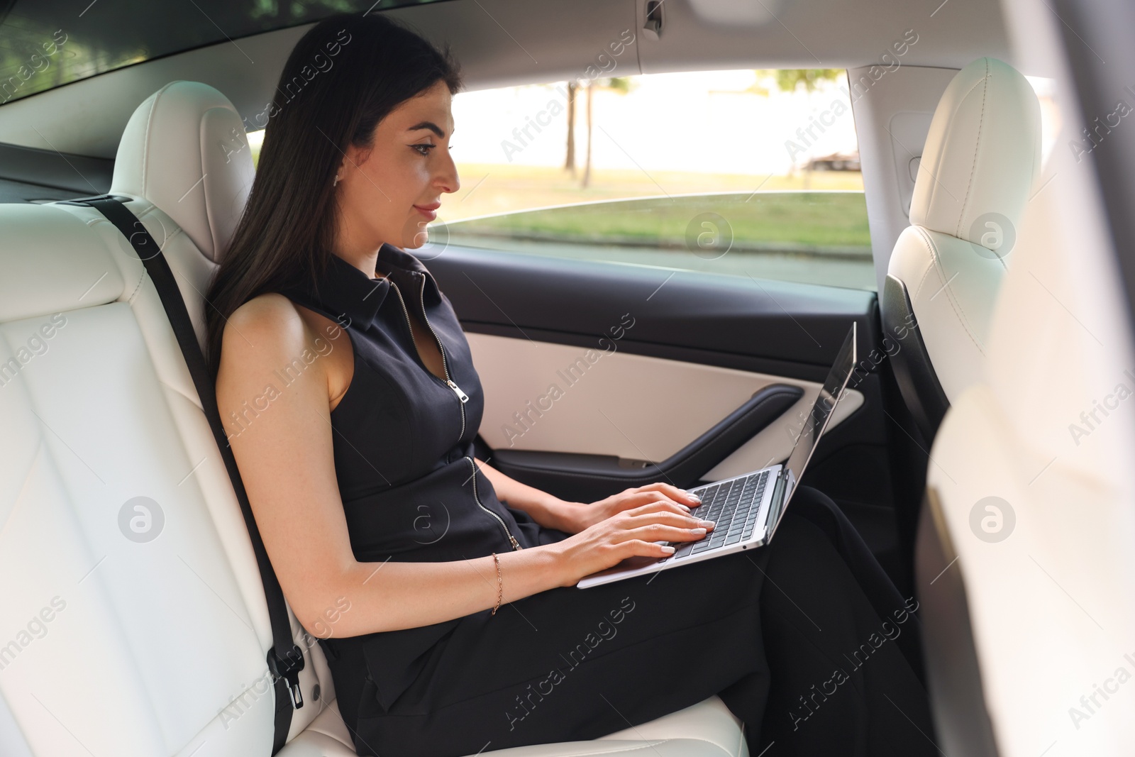 Woman using laptop in modern car, view from outside Photo of Woman using laptop in modern car, view from outside