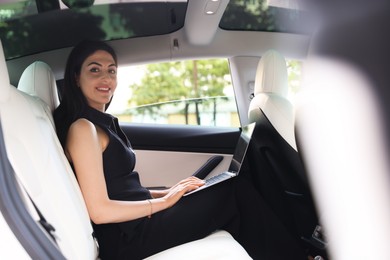 Photo of Woman using laptop in modern car, view from outside