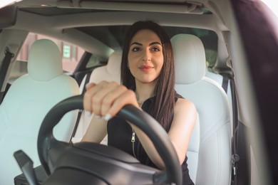 Photo of Woman behind steering wheel of modern car, view through windshield