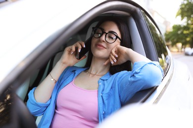 Photo of Woman talking on smartphone in car, view from outside