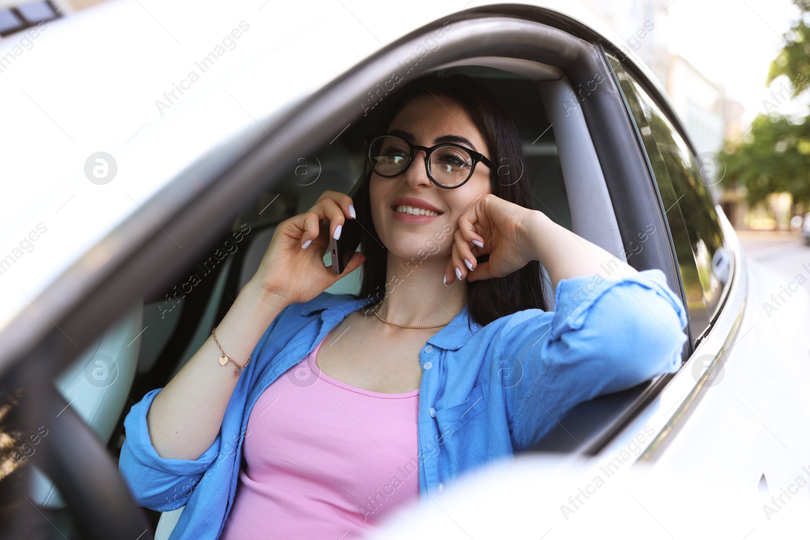 Photo of Woman talking on smartphone in car, view from outside