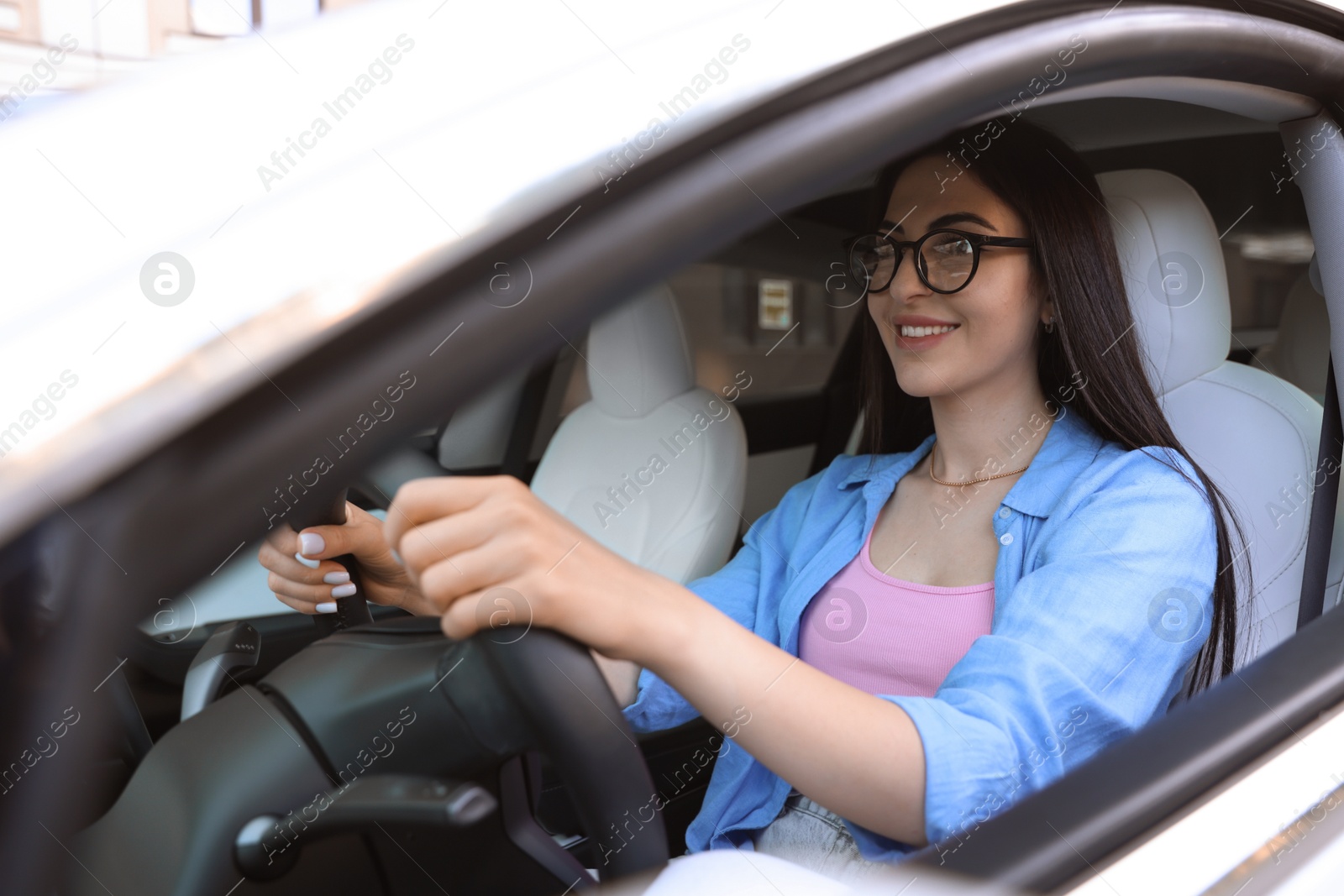 Photo of Woman behind steering wheel of modern car, view from outside