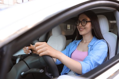 Photo of Woman behind steering wheel of modern car, view from outside