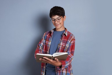 Photo of Teenage boy reading book on grey background