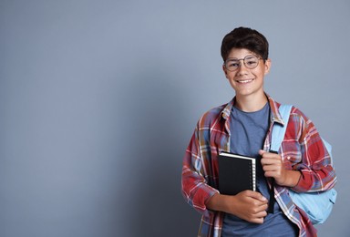 Photo of Teenage boy with notebook and backpack on grey background, space for text