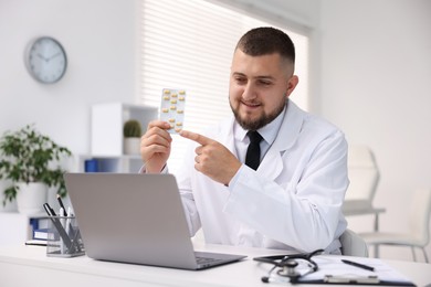Photo of Doctor with pills having online consultation via laptop in clinic