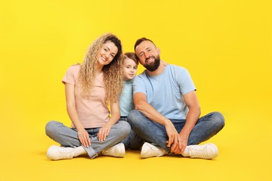 Photo of Happy family. Parents and their son posing on yellow background