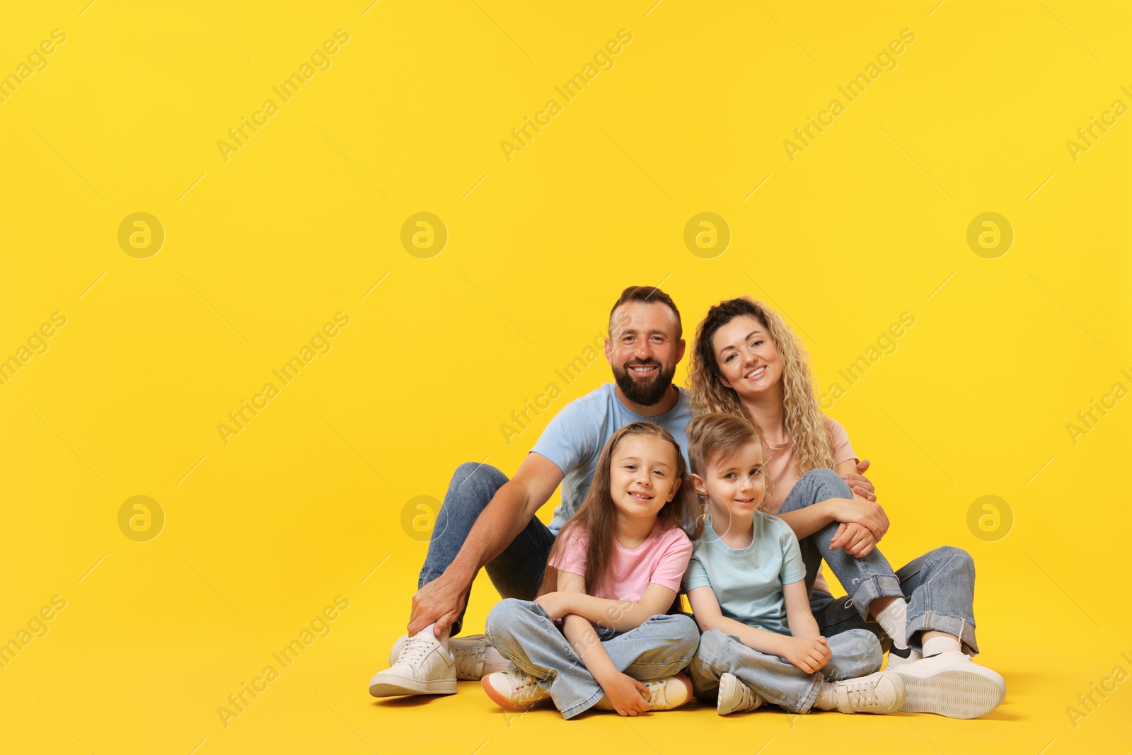 Happy family on yellow background. Space for text Photo of Happy family on yellow background. Space for text