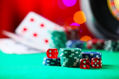 Photo of Casino chips and dice on green table against blurred lights, closeup. Space for text
