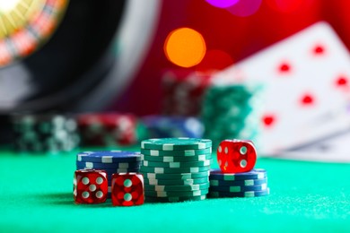 Photo of Casino chips and dice on green table against blurred lights, closeup