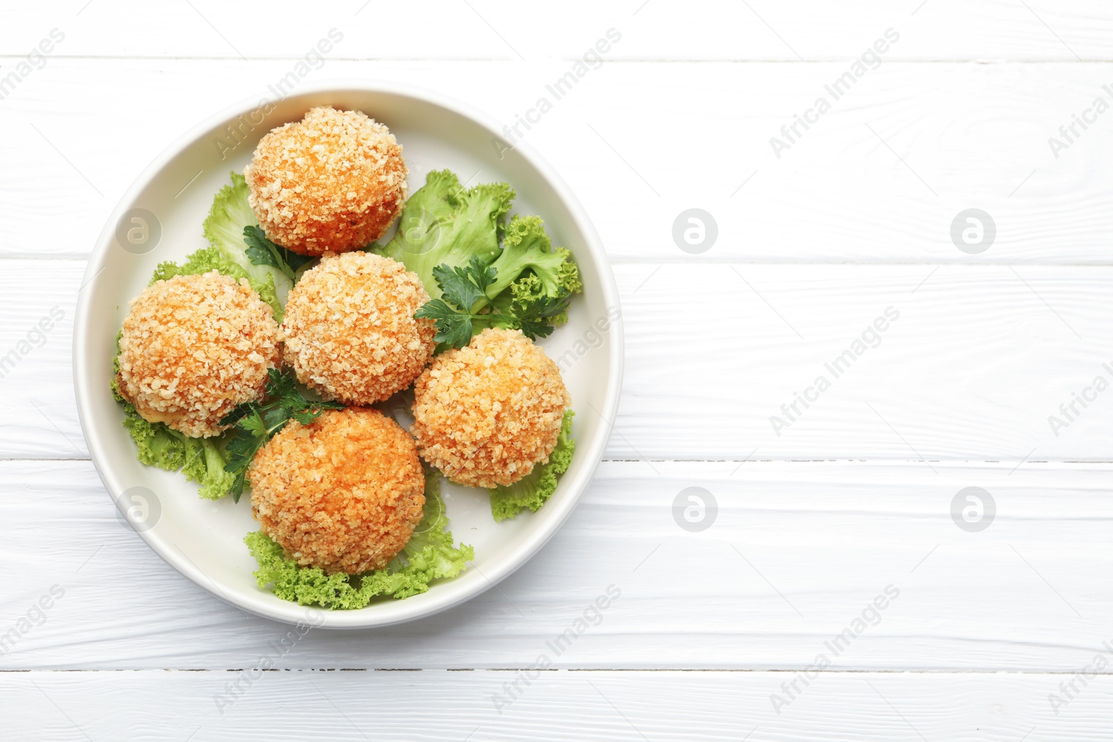 Delicious fried croquette balls with parsley and lettuce on white wooden table, top view. Space for text Photo of Delicious fried croquette balls with parsley and lettuce on white wooden table, top view. Space for text